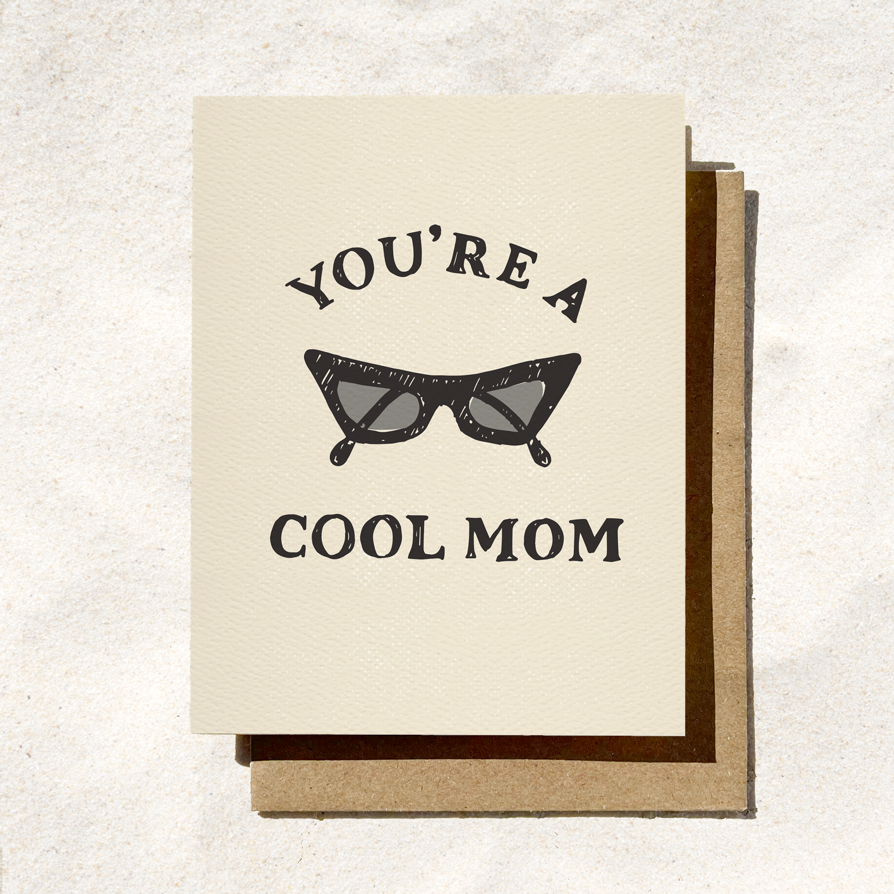Greeting card with a vintage sunglasses illustration and "You're a Cool Mom" text, set on a textured beige background.