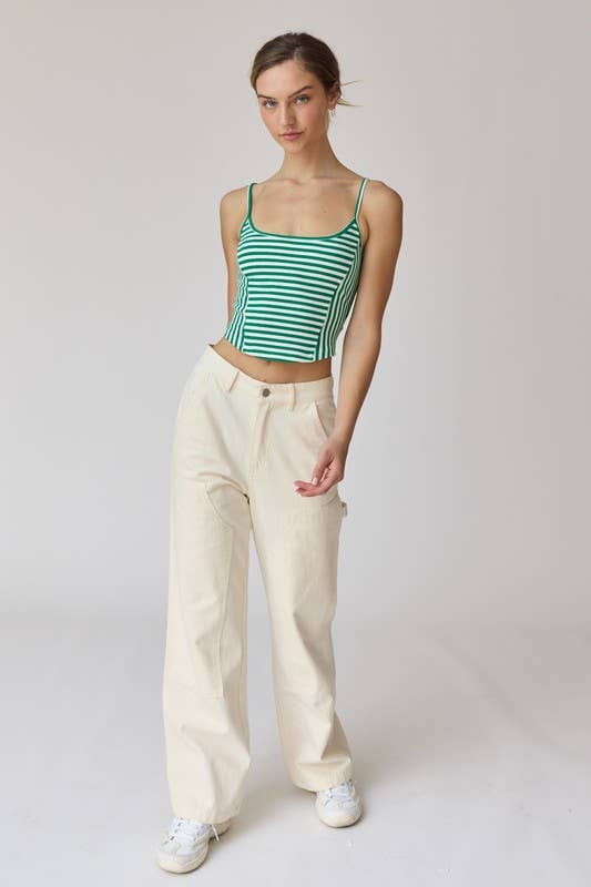 Woman wearing a green and white stripe rib knit tank top with thin straps and high-waisted beige shorts.