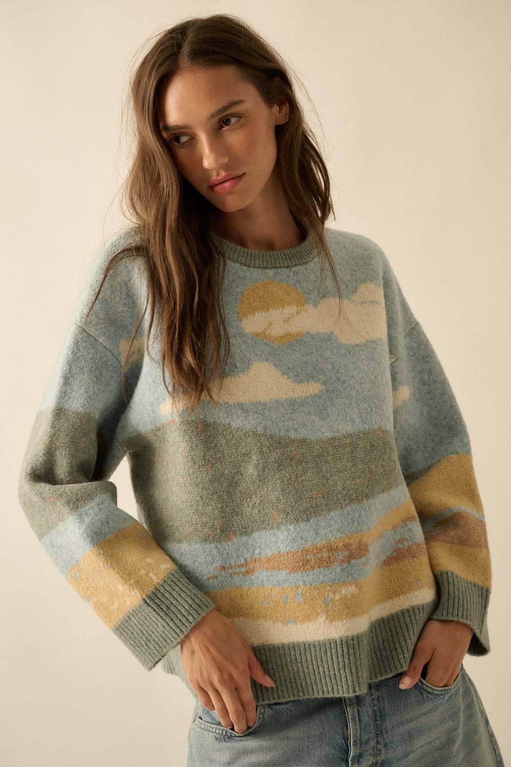 Woman wearing a sweater with a landscape design on a plain background