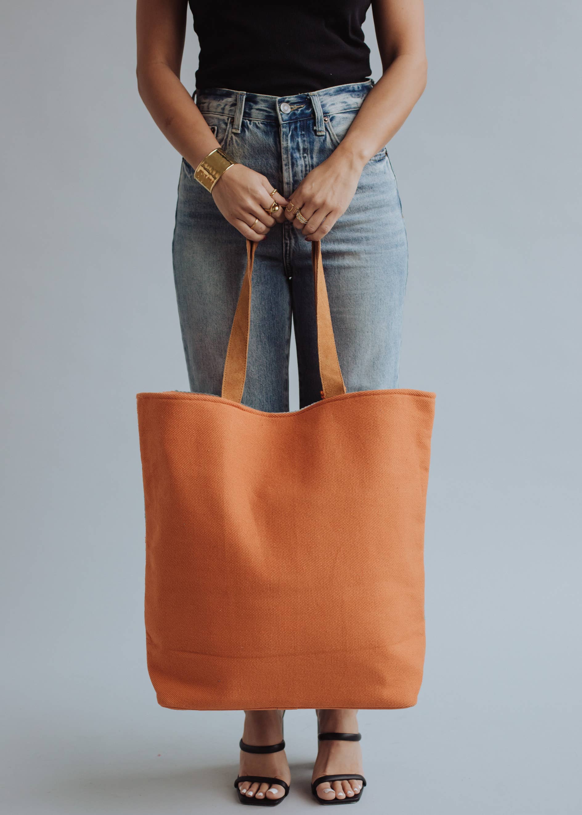 Tote bag with orange and sage green zigzag design and tassel, styled with denim jeans