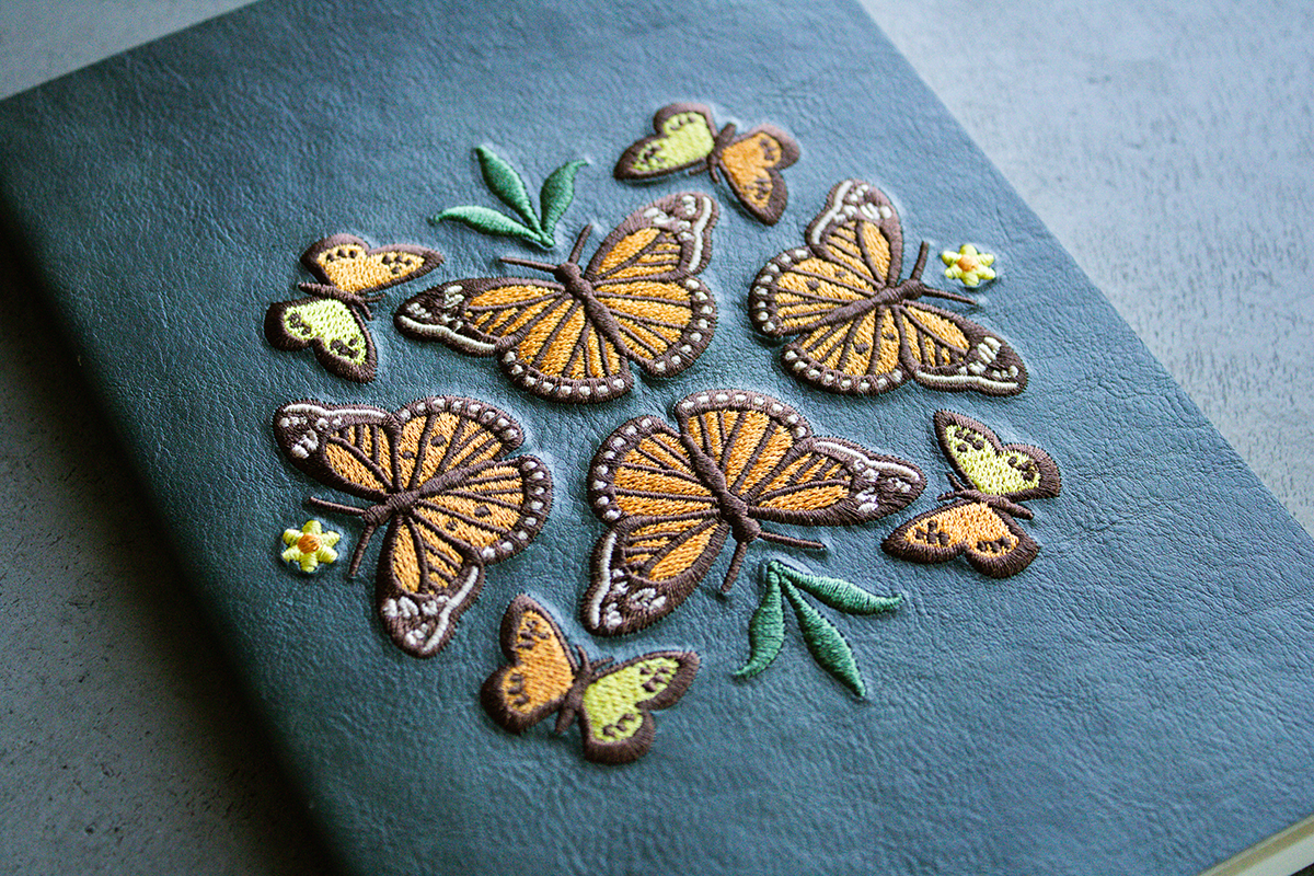 Green notebook with embroidered monarch butterfly design.