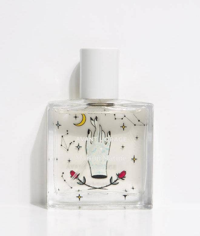 Maison Matine Avant l’Orage perfume bottle with celestial illustrations, placed among citrus fruits and sample vials on blue fabric