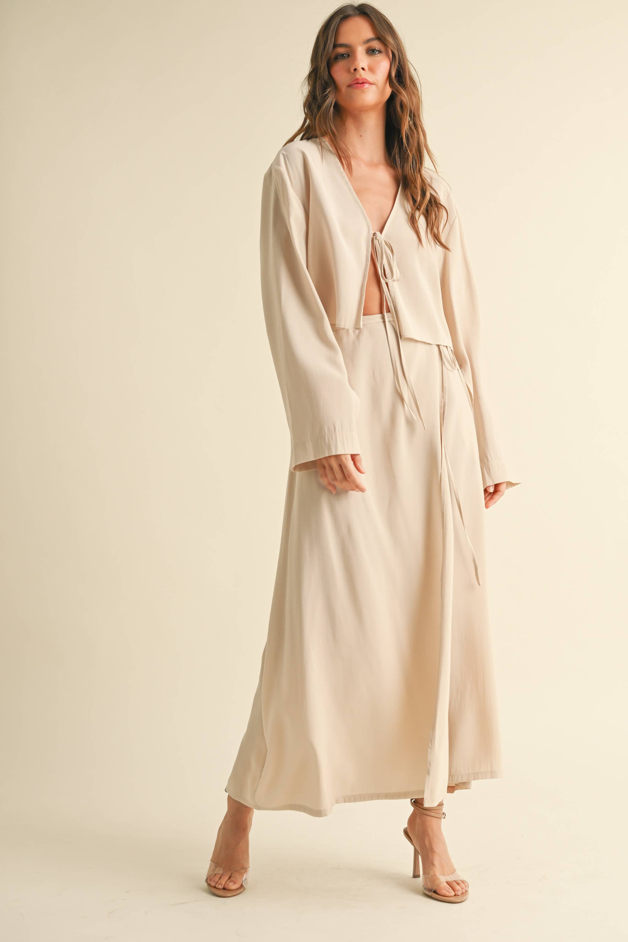 Woman wearing a beige tie-front long sleeve top and matching wrap maxi skirt, styled as a coordinated skirt set.