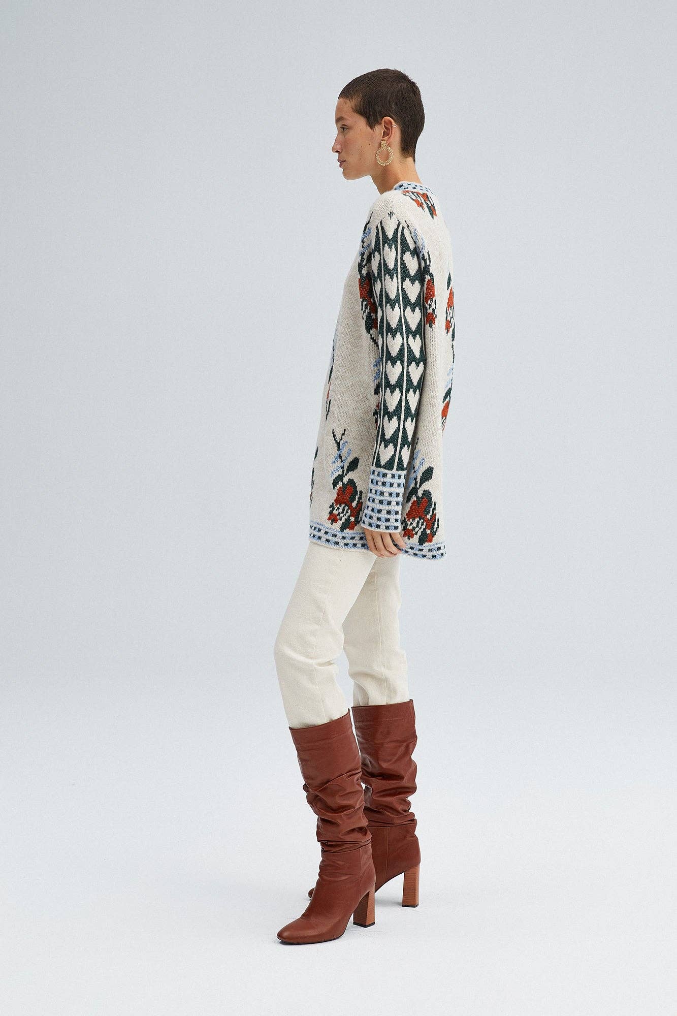 Woman wearing a Fair Isle floral knit sweater with long sleeves and mixed pattern detailing in red, green, and blue.