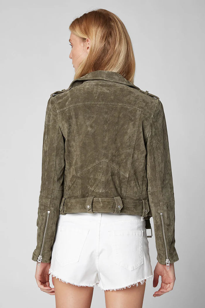 Person wearing a green suede jacket and white shorts on a plain background