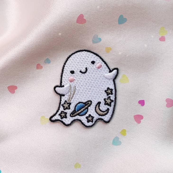 Iridescent glitter ghost patch with cosmic details - planet, moon, and stars, bordered by a shimmering gold trim.