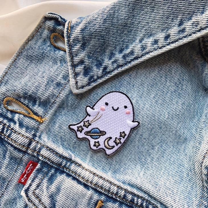 Iridescent glitter ghost patch with cosmic details - planet, moon, and stars, bordered by a shimmering gold trim.