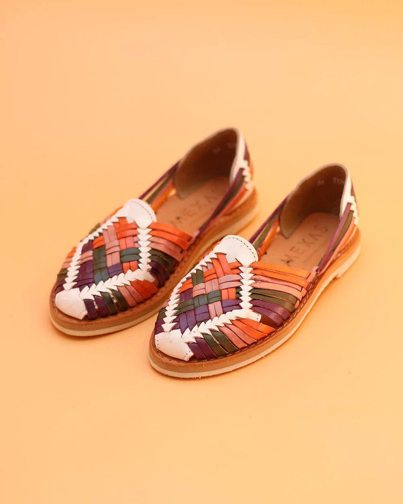 Handmade Chapulines sandals crafted from 100% genuine leather, displayed on a rustic wooden background.