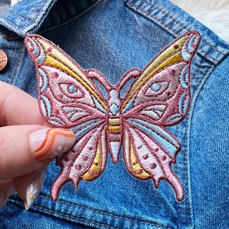 Embroidered patch of a luminous butterfly with intricate, mystical designs.