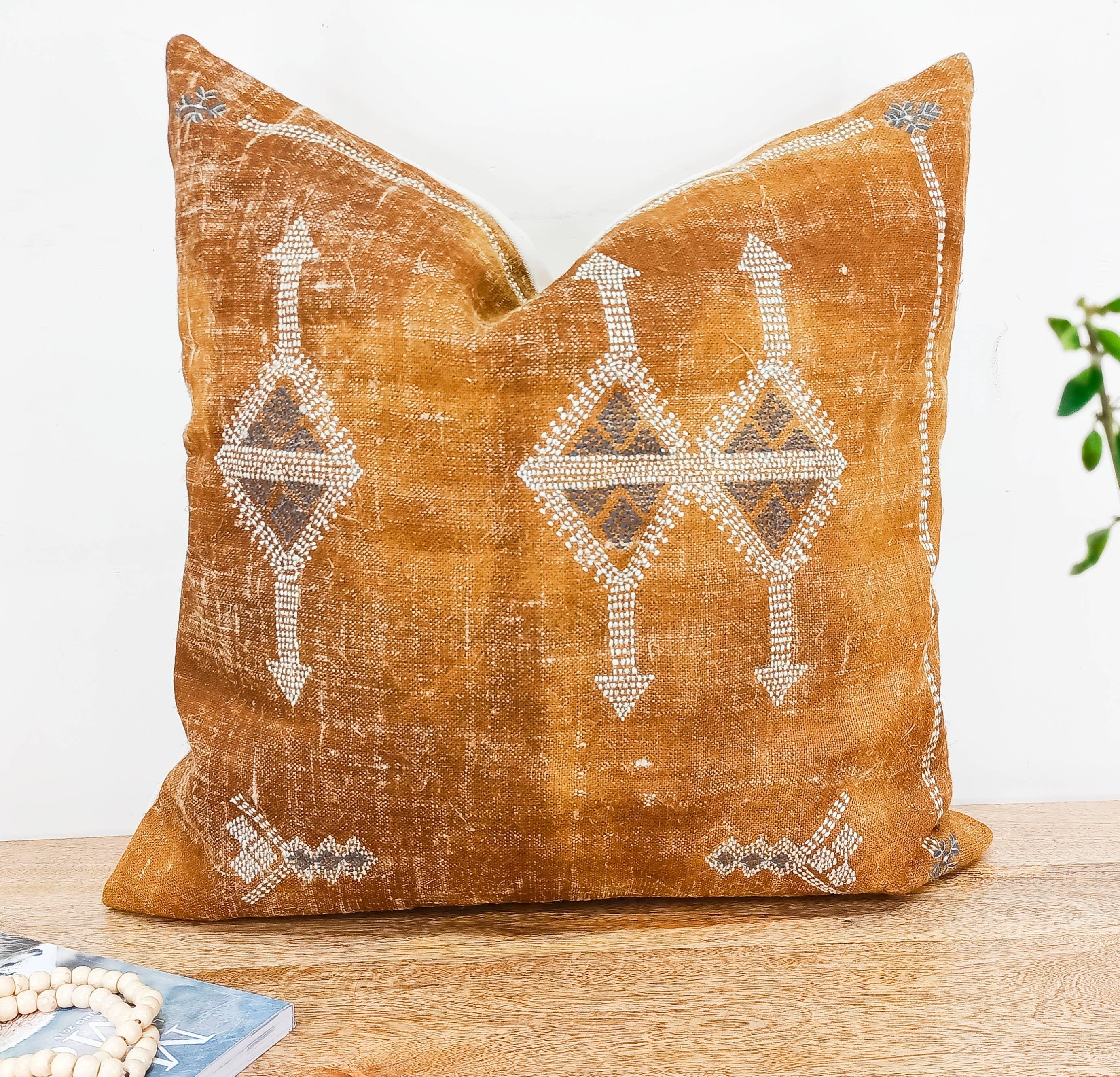 Image of the 'Moroccan Rug Design Embroidered Pillow Cover', highlighting the hand-embroidered motifs, the hand-painted color, and the handmade cotton yarn tassels.
