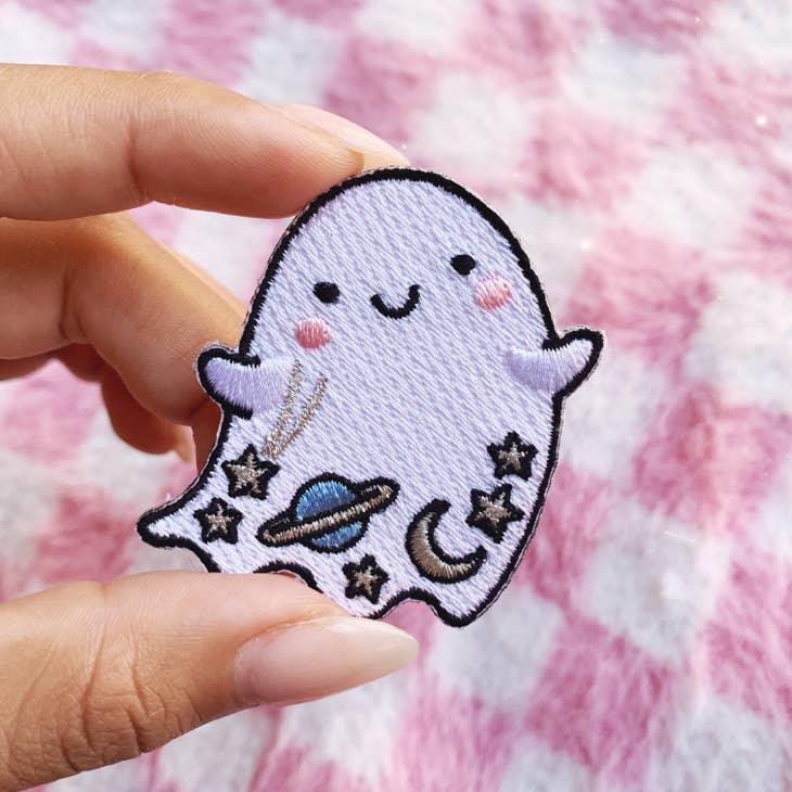 Iridescent glitter ghost patch with cosmic details - planet, moon, and stars, bordered by a shimmering gold trim.