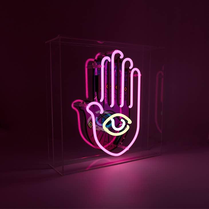 Yellow, pink, and white Neon Hamsa Hand Light encased in a glossy acrylic box with printed graphics by FORMA.