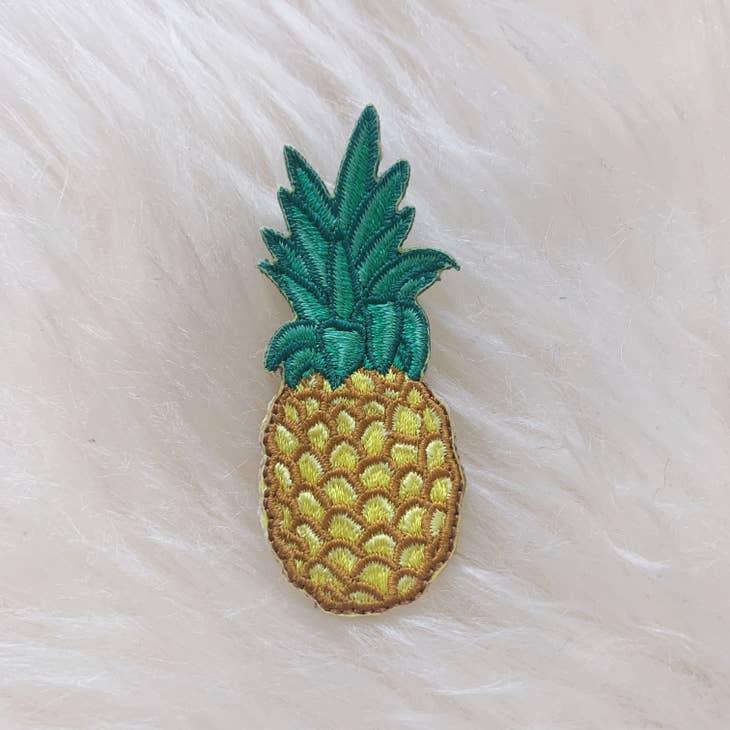 Golden embroidered pineapple patch with detailed green leaves.