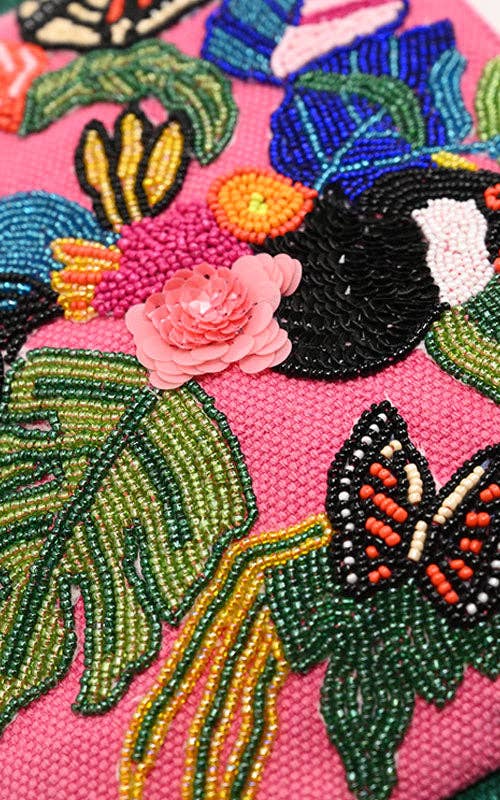 Pink beaded clutch with toucan, butterfly, and tropical floral embroidery, green fringe sides, and silver chain strap.