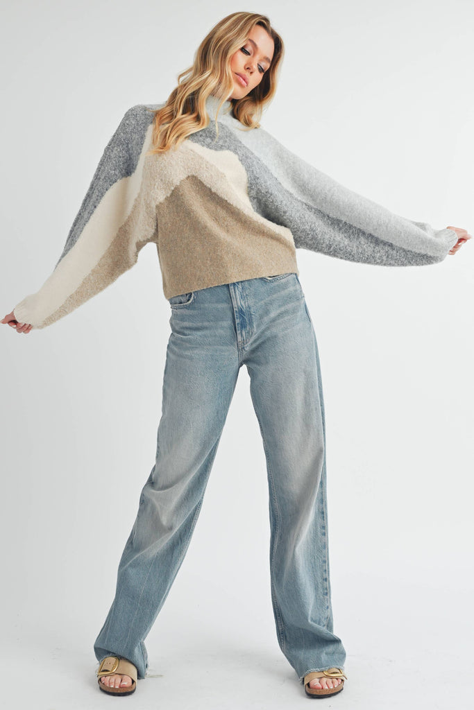 Woman wearing a patterned sweater and jeans on a white background