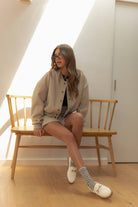 Model wearing a wool-blend jacket and mini skirt set in a neutral tone, styled with a striped tee and relaxed fit, showcasing casual elegance.