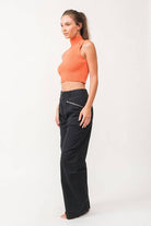 Woman wearing a cropped orange mock neck ribbed knit sweater.