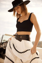 Woman wearing a white ribbed knit crop top with a sweetheart neckline and wide straps.