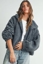 Woman wearing a ribbed gray faux-fur jacket paired with a white tank top and jeans.