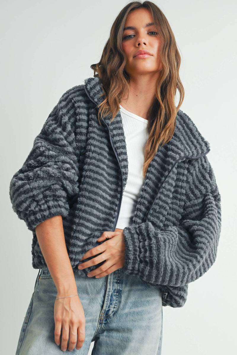 Woman wearing a ribbed gray faux-fur jacket paired with a white tank top and jeans.