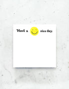 A jumbo desk pad with a cheerful yellow smiley face and the message “Have a nice day” written in bold, playful lettering.