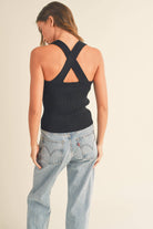Model wearing a sleeveless ribbed knit top with deep V-neck and cross-back strap detail.