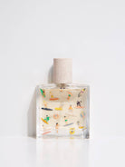 Maison Matine Bain de Midi perfume bottle with playful illustrations and white cap, styled with flowers and modern props.