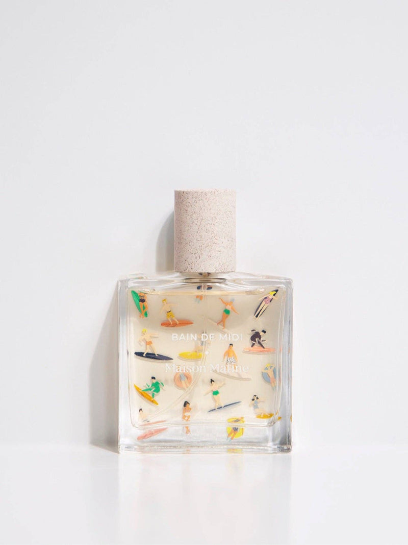 Maison Matine Bain de Midi perfume bottle with playful illustrations and white cap, styled with flowers and modern props.