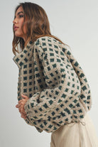 Woman wearing a beige and green checkered fleece jacket with a zip closure, paired with a white crop top and beige corduroy pants.