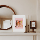 Helping Hands Print featuring diverse women standing together and holding a surfboard, framed in a wooden frame.