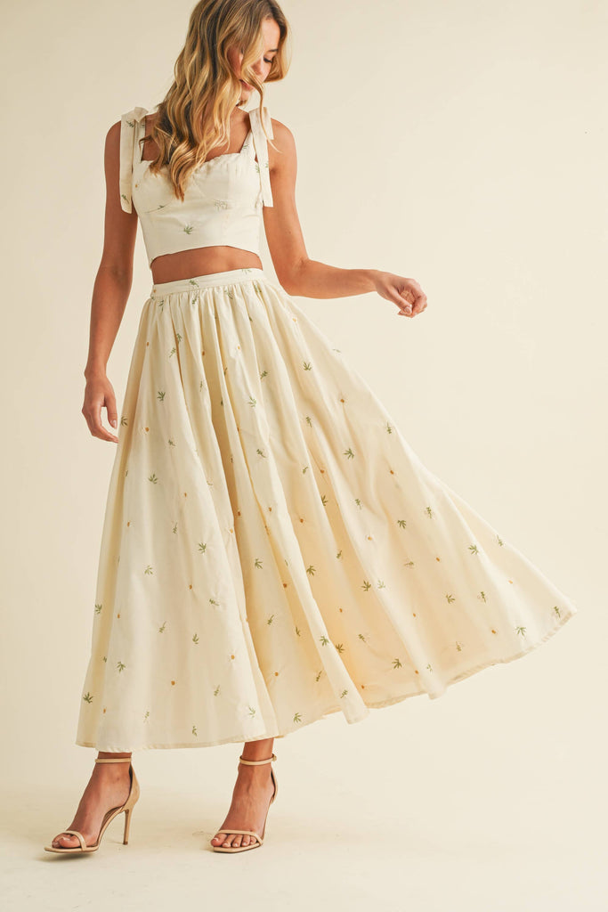 Light cream two-piece set with small floral embroidery, featuring bow-tie strap top and flowy maxi skirt