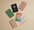 Collection of colorful notebooks and a pen on a beige background