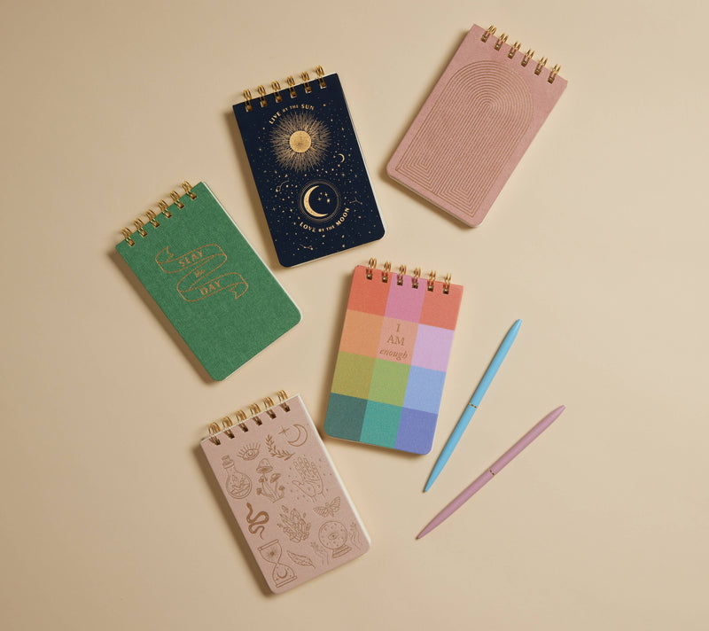 Collection of colorful notebooks and a pen on a beige background