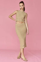 Woman wearing a beige sleeveless crochet top and midi skirt set.