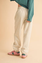 Woman wearing light heather beige fleece jogger pants with a relaxed fit and elastic waistband.
