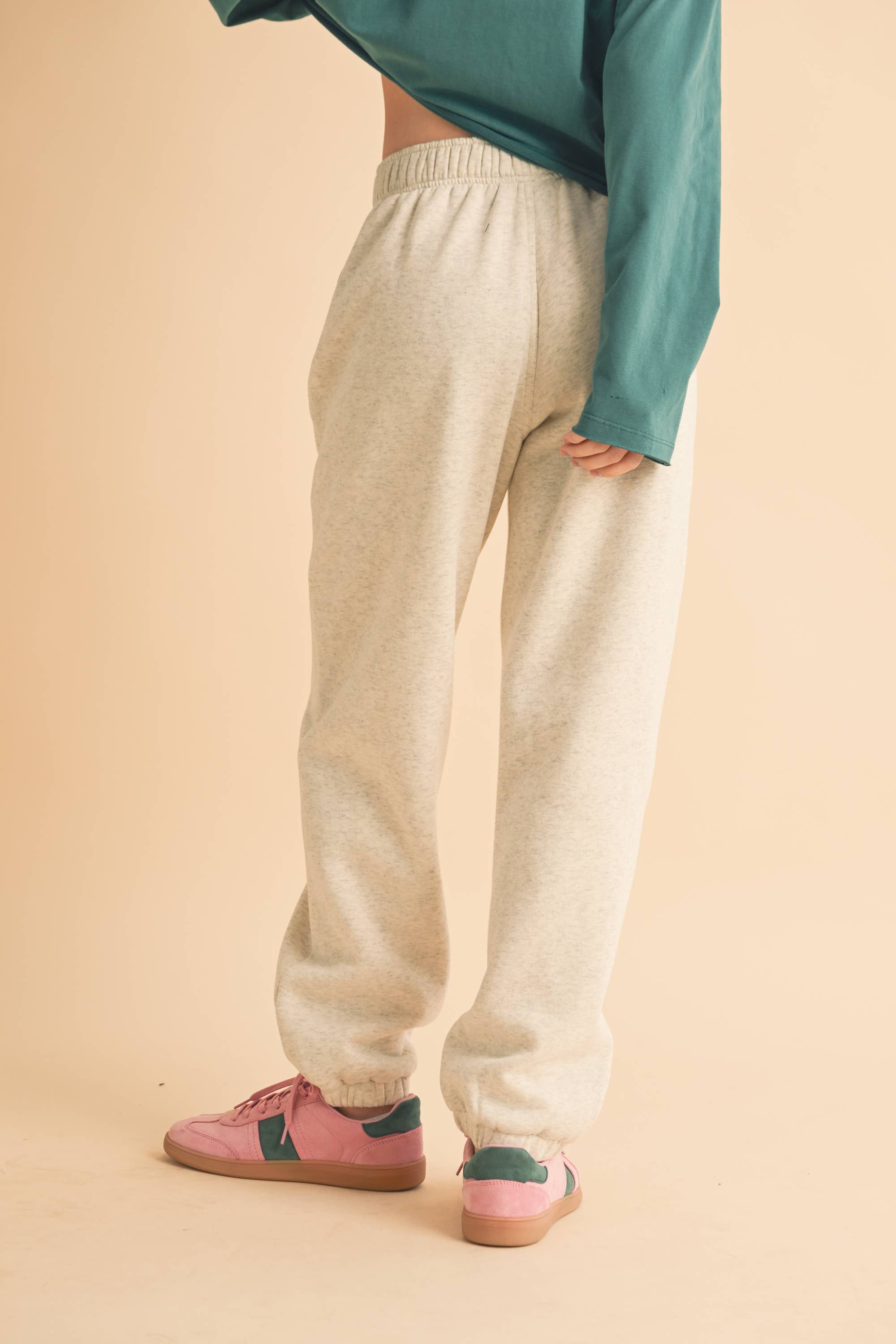 Woman wearing light heather beige fleece jogger pants with a relaxed fit and elastic waistband.