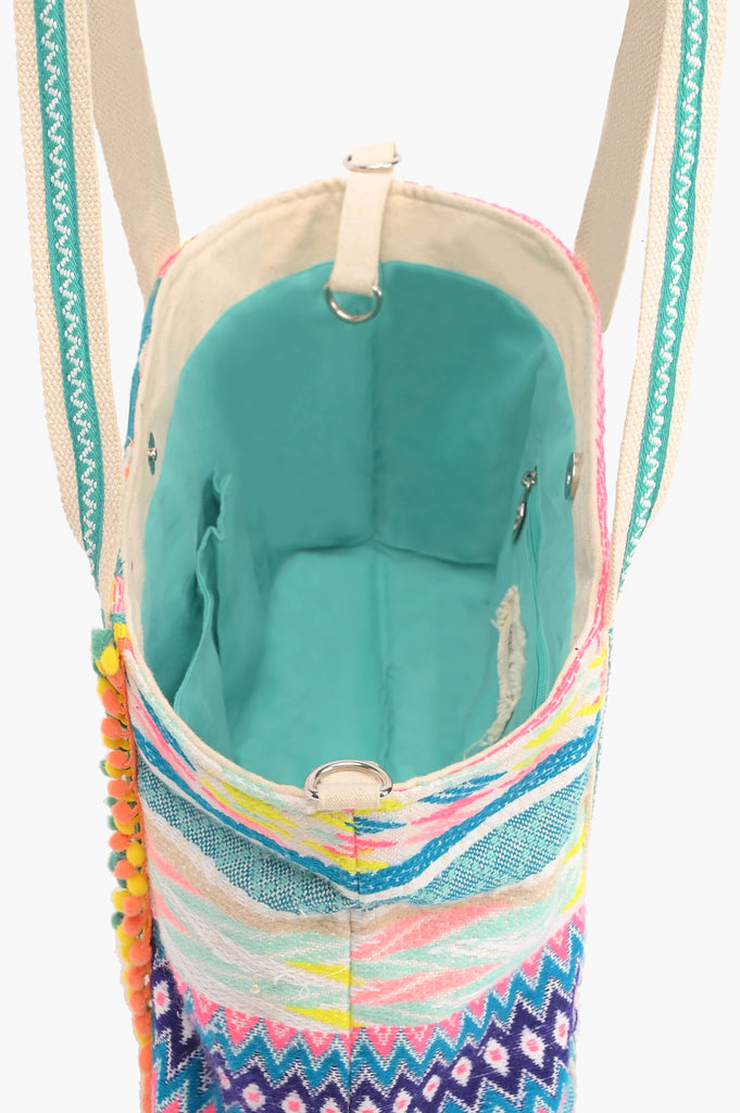 Multicolor embroidered crossbody bag with abstract beading, patterned sides, pom-pom trim, and detachable strap.