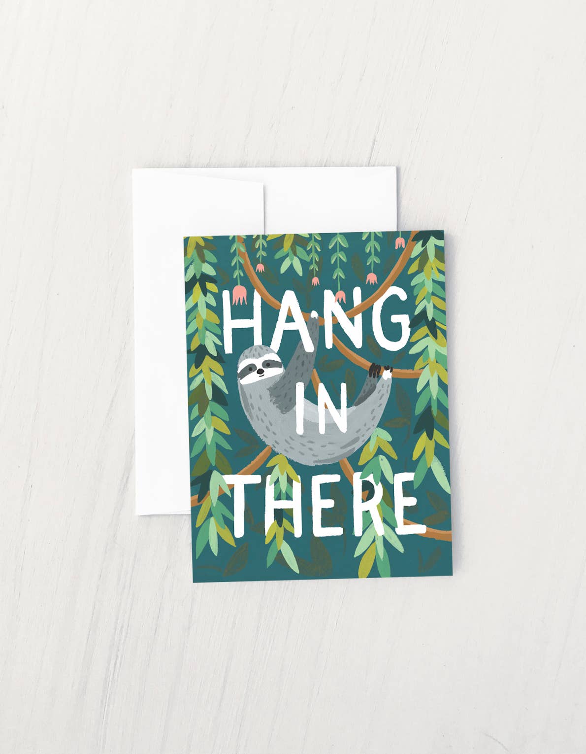 Greeting card with a sloth hanging from a tree branch and the phrase “Hang in There” surrounded by green leaves.