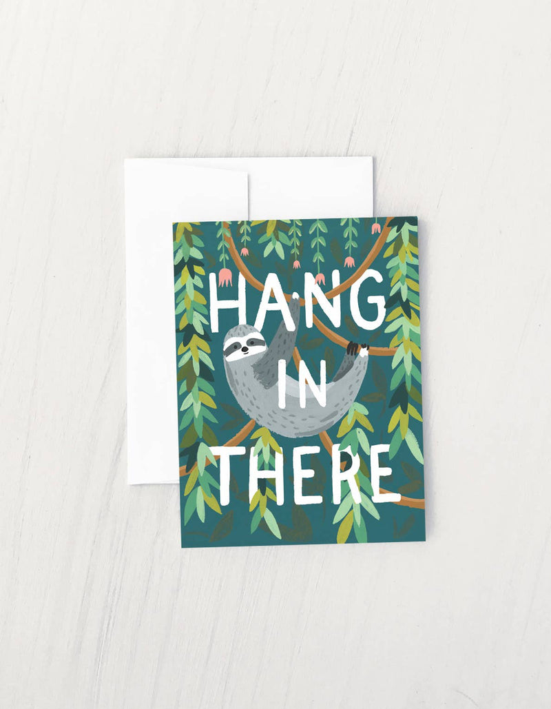 Greeting card with a sloth hanging from a tree branch and the phrase “Hang in There” surrounded by green leaves.