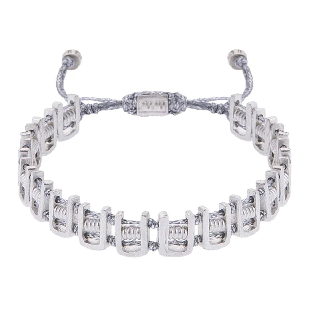 A silver-colored bracelet with adjustable ends and intricate design, featuring a mix of bronze and silver materials.