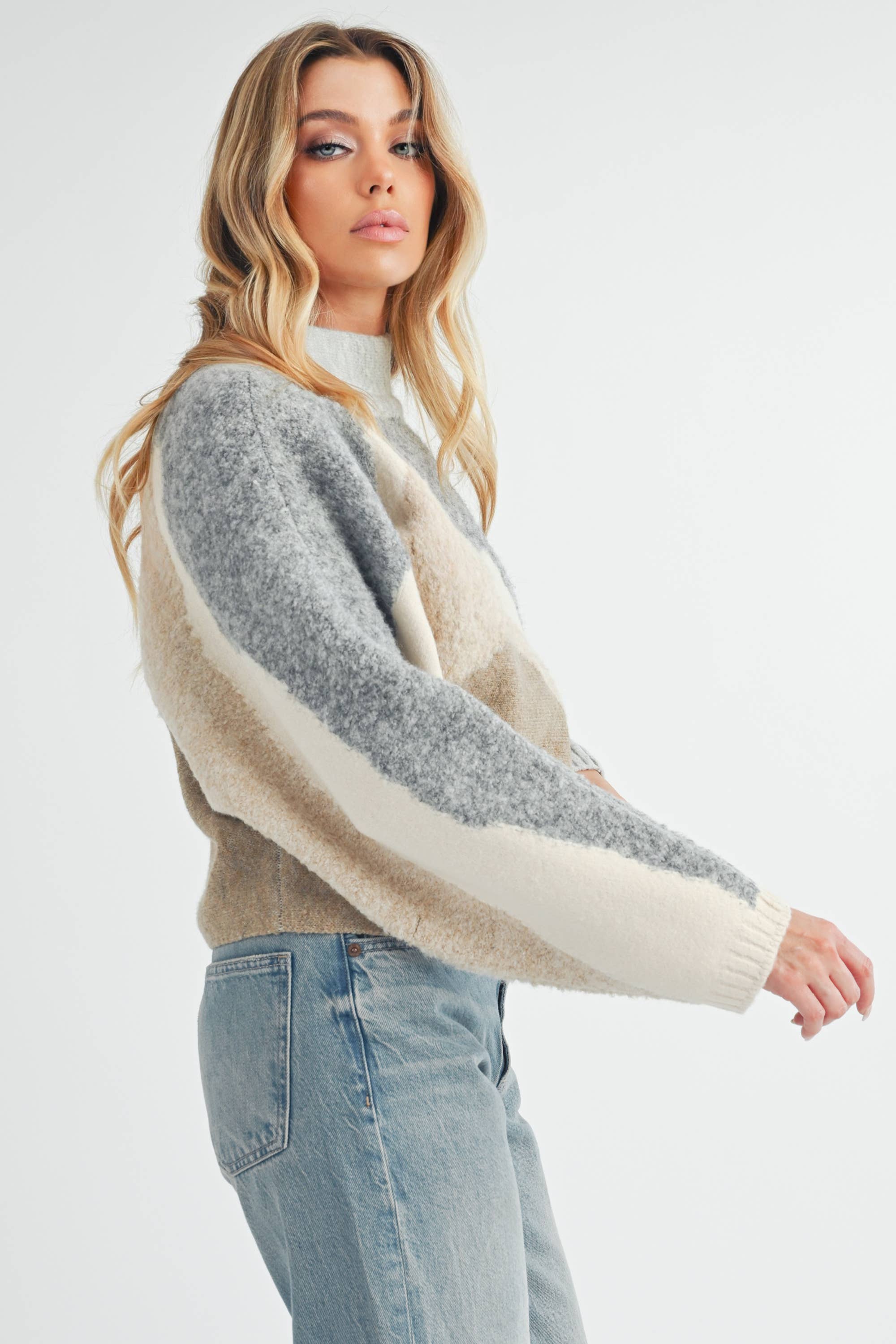 Front and back view of a woman wearing a color-block knit sweater in grey, cream, and taupe with a relaxed fit.
