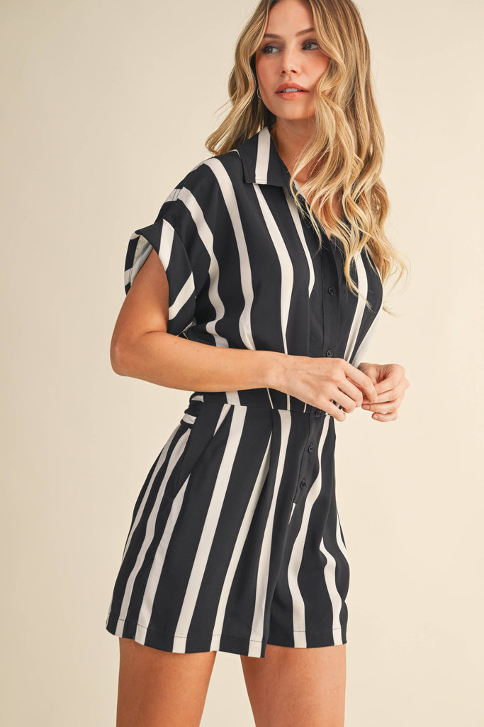Woman wearing a black and white striped dress against a beige background