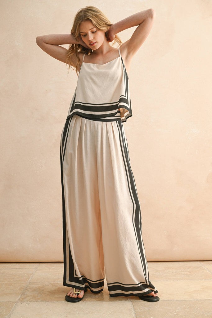 Woman wearing a cream and black striped two-piece set with a flowy top and wide-leg pants.