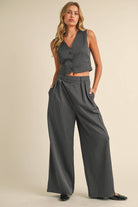 Woman wearing a sleeveless pinstriped vest and matching high-waisted wide-leg trousers.