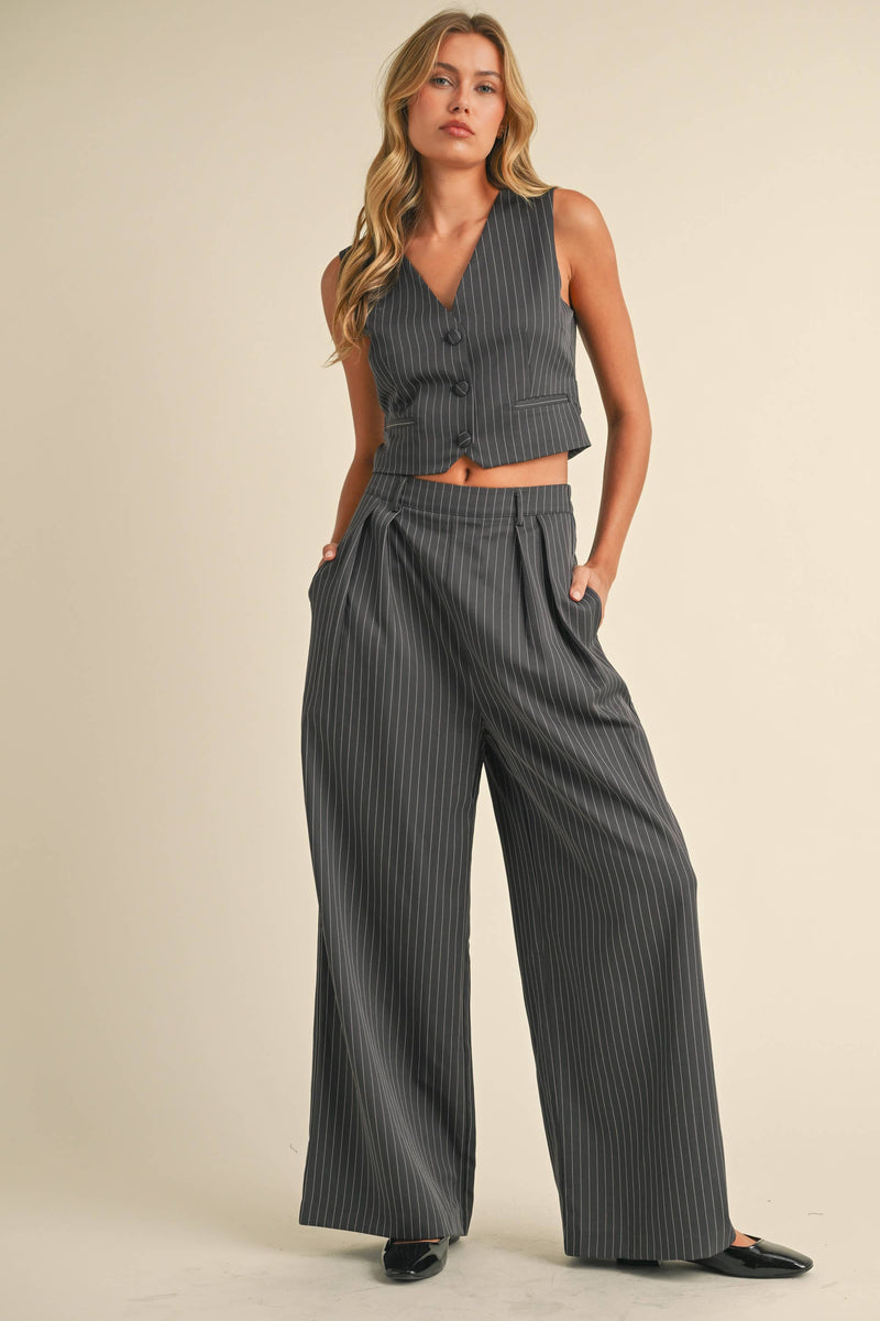 Woman wearing a sleeveless pinstriped vest and matching high-waisted wide-leg trousers.