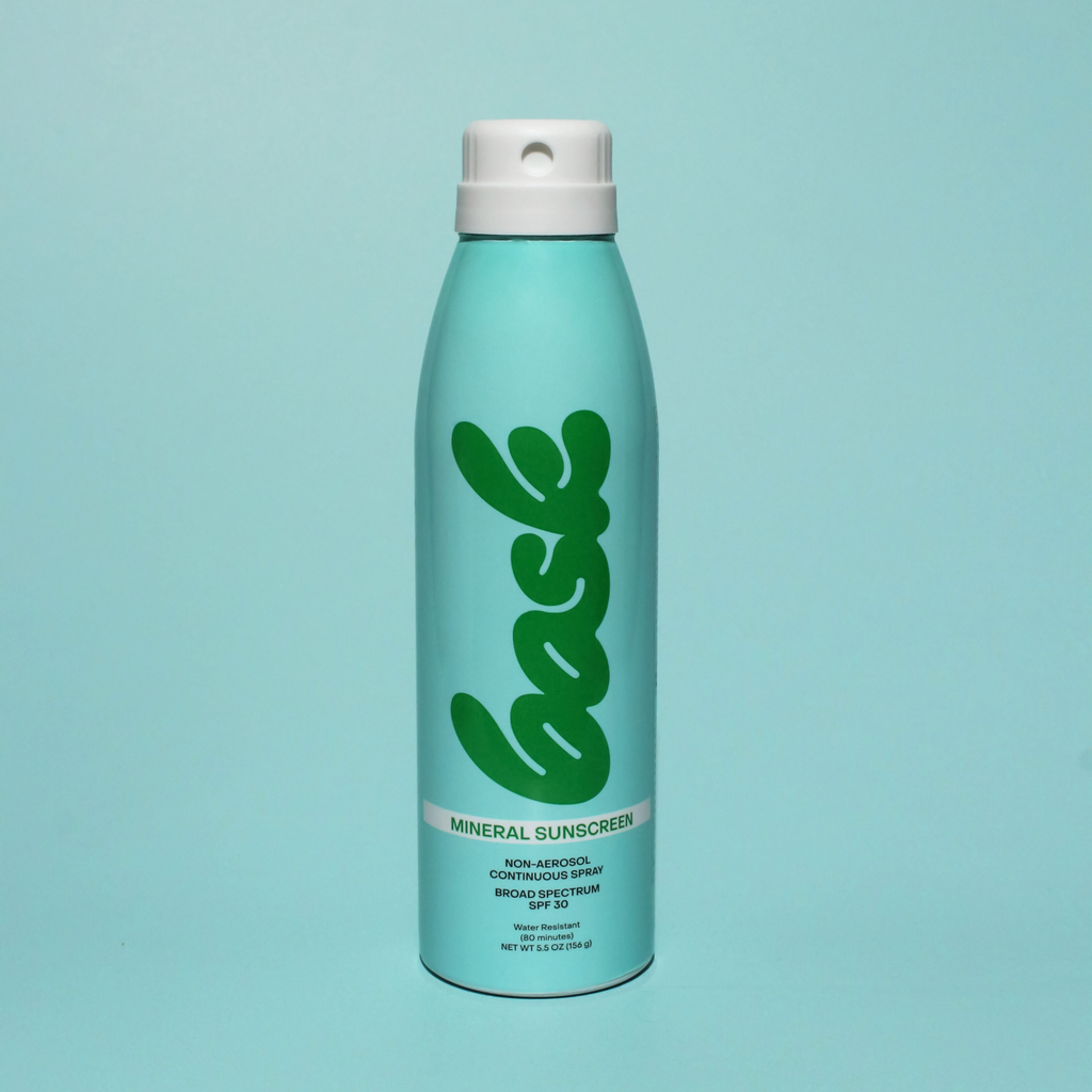 Blue sunscreen spray bottle with green logo on light blue background
