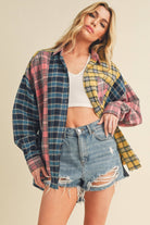 Woman wearing an oversized plaid colorblock flannel shirt in pink, yellow, and navy tones with raw hems.