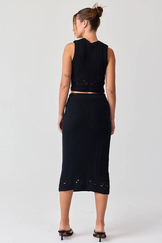 Woman wearing a black sleeveless crochet top and midi skirt set.