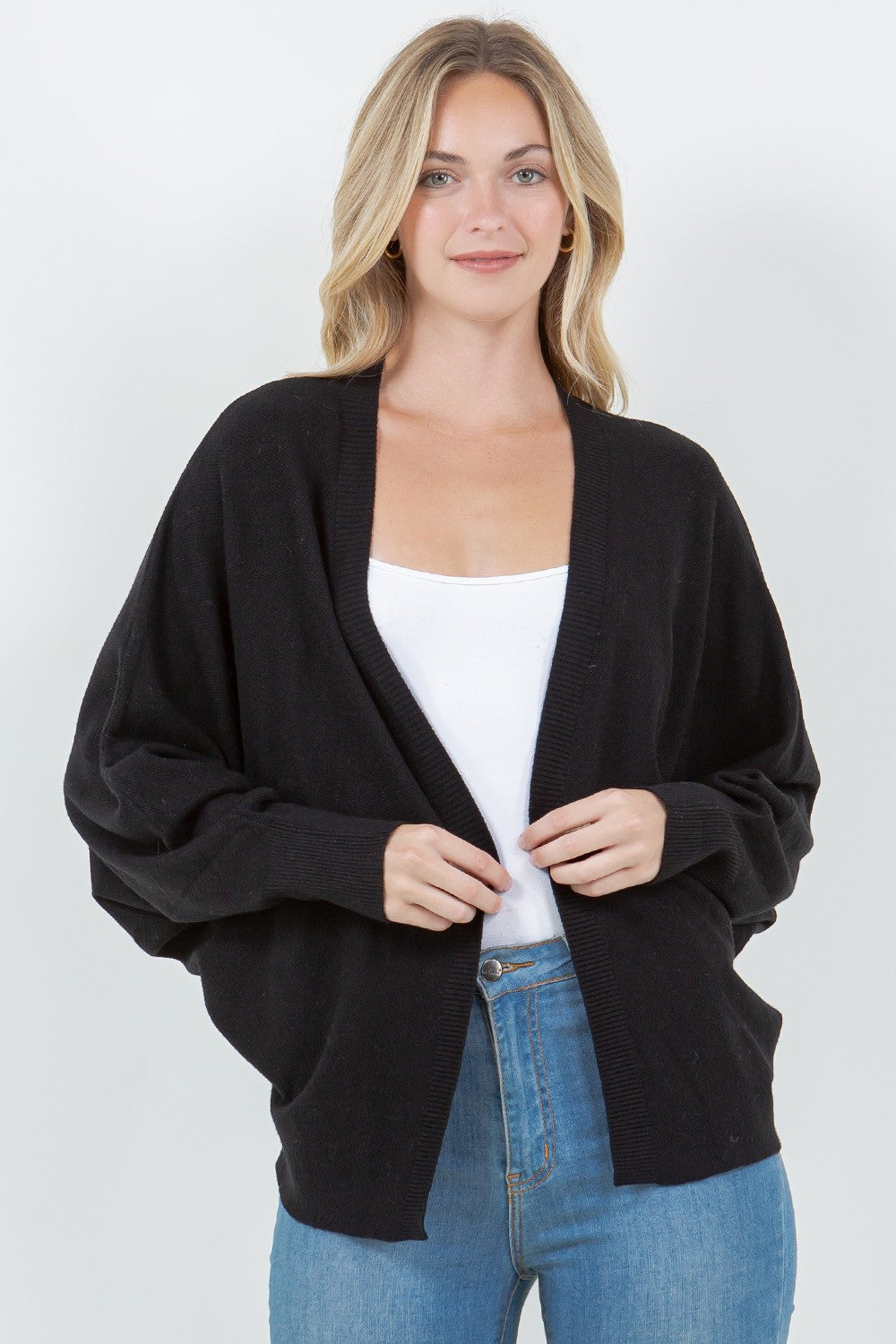 Woman wearing a black open-front cardigan with ribbed trim.