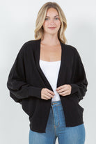 Woman wearing a black open-front cardigan with ribbed trim.